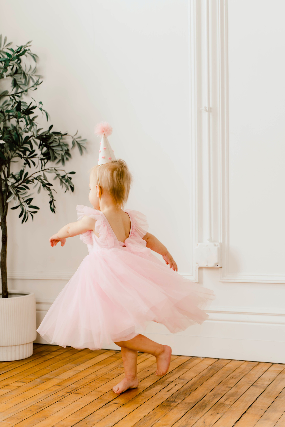 A little girl twirling in a pink party dress